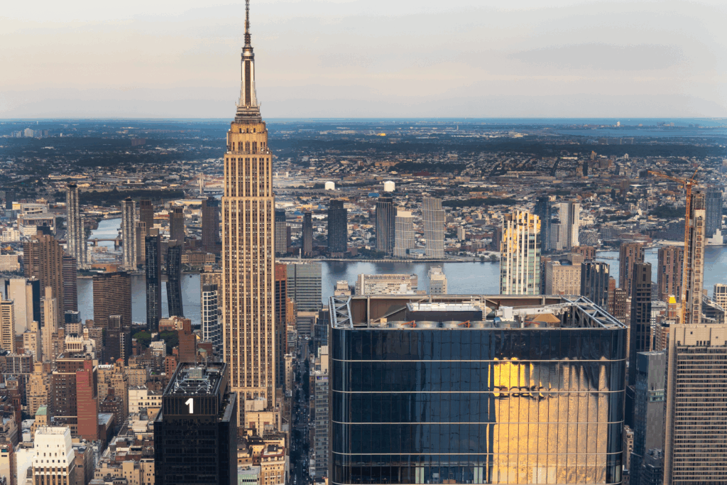 Manhattan skyline at golden hour seen from The Edge at Hudson Yards, glowing with reflections of sunset light