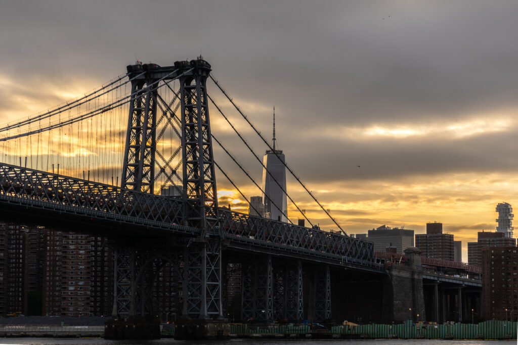 Williamsburg Bridge and DUMBO waterfront at sunset with golden reflections on the East River